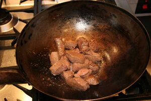 Stewing steak being browned in a wok